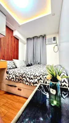 a bedroom with a bed and a vase with flowers on a table at Cozy RC 2BR w loft Netflix Prime KTV Games in Manila