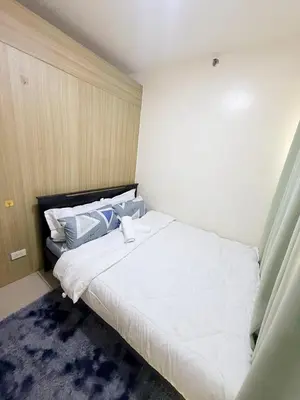 a bedroom with a large white bed with blue pillows at 2BR SHORE FAMILY GROUPs AFFORDABLE STAYCATION in Manila