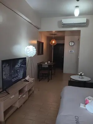 a living room with a bed and a tv and a table at M&N Condotel in Manila
