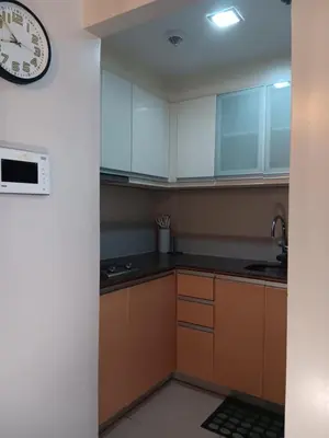 a kitchen with brown cabinets and a clock on the wall at M&N Condotel in Manila