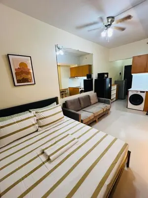 a bedroom with a bed and a living room at Unit 23L T-B The Pearl Place Ortigas in Manila