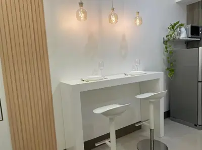 a white counter with two stools in a kitchen at Cityscape Suite in Manila