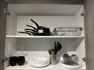 a shelf with plates and glasses and utensils at Cityscape Suite in Manila