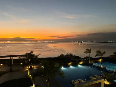 a swimming pool with a view of the ocean at sunset at Playful 1BR With Magnificant Bayview Garden View Near Okada, Solaire, Aiports in Manila