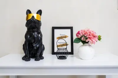 a black cat statue sitting on a shelf with a picture and flowers at Uptown Parksuites Sky Garden Flr Bright Airy 2 BR balcony in Manila