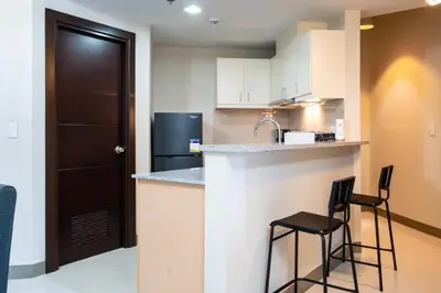a kitchen with a counter and two bar stools at Uptown Parksuites Sky Garden Flr Bright Airy 2 BR balcony in Manila