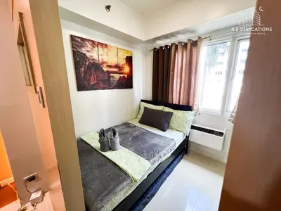 a small bed in a room with a window at RE Staycations in Manila