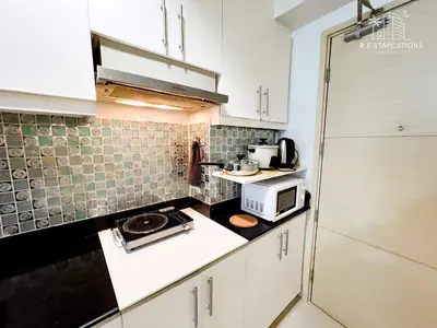 a small kitchen with white cabinets and a microwave at RE Staycations in Manila