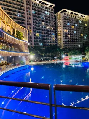 a large swimming pool in front of buildings at night at Azure staycation by Scarlet Suites in Manila