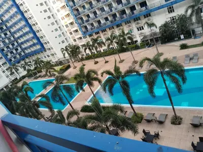 an aerial view of a pool with palm trees and buildings at MOA Sea Residences Condo in Manila