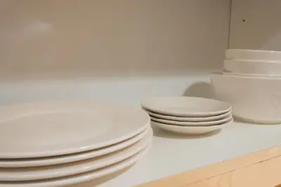 a pile of white plates and bowls on a counter at Uptown BGC Spacious Unit - 1 Queen bed and Bunkbed in Manila