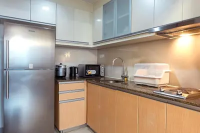 a kitchen with white cabinets and a stainless steel refrigerator at Uptown BGC Spacious Unit - 1 Queen bed and Bunkbed in Manila