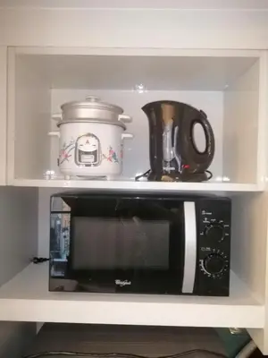a microwave on a shelf with a pot and a tea kettle at KL Tower Cosy Studio with City and Park View in Manila
