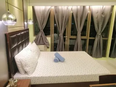 a bed with a pillow and a blue tape on it at KL Tower Cosy Studio with City and Park View in Manila