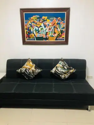 a black couch with two pillows sitting under a painting at Sea Residences-Booking Reservation in Manila