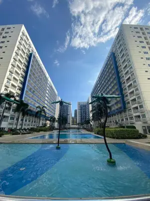 a swimming pool in the middle of two tall buildings at Sea Residences-Booking Reservation in Manila