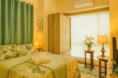 a bedroom with a bed with green curtains and a window at The Beacon Skyview 2BR La Suitez4307 in Manila