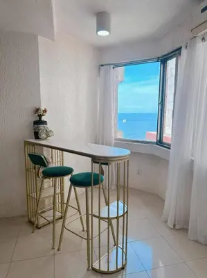 a kitchen with a table and stools in front of a window at Marbella Tower 2 in Manila