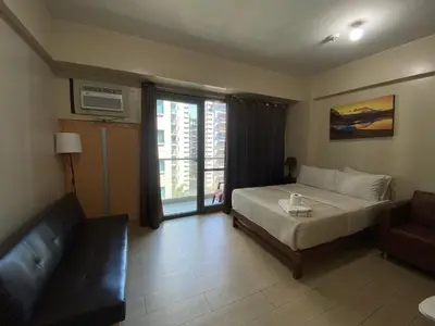 a bedroom with a bed and a couch and a window at the palm tree villas by kath in Manila