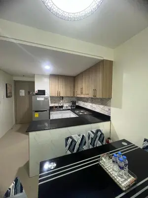 a kitchen with wooden cabinets and a black counter top at 2Br Suite Shore Residences by JMS in Manila