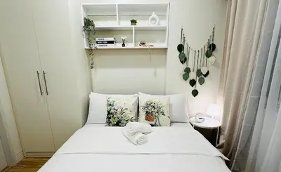 a small bedroom with a bed with white sheets and pillows at Getaway Haven at Southwoods, Biñan with Fast Internet in Biñan