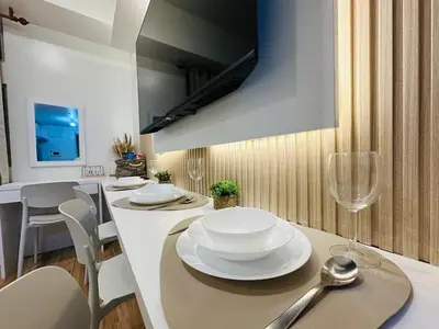 a dining room with a table with white plates and wine glasses at Getaway Haven at Southwoods, Biñan with Fast Internet in Biñan