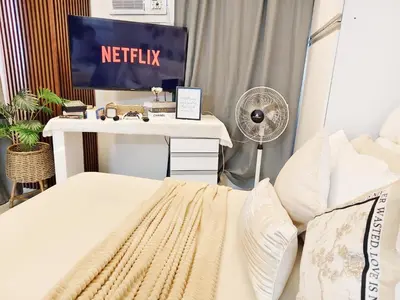 a bedroom with a bed and a desk with a netflix sign at Affordable Staycation in Dasma Green 2 Residence in Dasmariñas