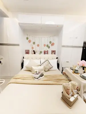 a white bedroom with a large bed and two tables at Affordable Staycation in Dasma Green 2 Residence in Dasmariñas