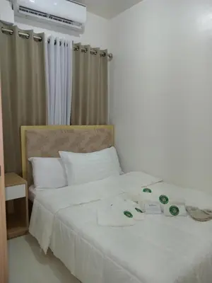 a hotel room with a white bed with white sheets at Condo Next Door PH in Manila