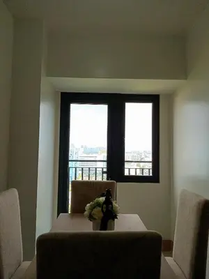 a dining room with a table and two windows at Condo Next Door PH in Manila