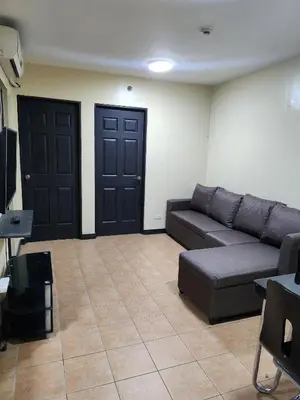 a living room with a couch and two black doors at 2BR Condo near BGC in Manila