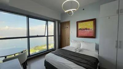 a bedroom with a bed with a view of the ocean at 3BR Grand Riviera Suites by MrSayla in Manila