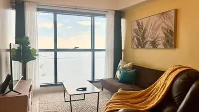a living room with a couch and a large window at 3BR Grand Riviera Suites by MrSayla in Manila