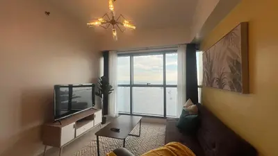 a living room with a television and a large window at 3BR Grand Riviera Suites by MrSayla in Manila