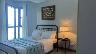 a bedroom with a bed and a lamp and a window at 3BR Grand Riviera Suites by MrSayla in Manila