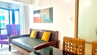 a living room with a couch with yellow pillows at 1BR Grand Riviera Suites by MrSayla in Manila