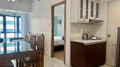 a kitchen with a table and a bed in a room at 1BR Grand Riviera Suites by MrSayla in Manila