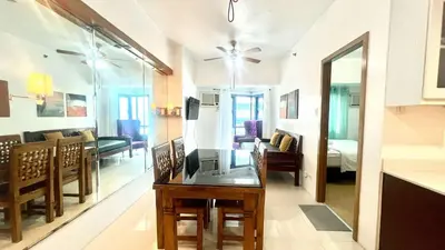a kitchen and a living room with a table in a room at 1BR Grand Riviera Suites by MrSayla in Manila