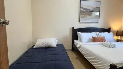 a bedroom with two beds and a blue ottoman at 1BR Grand Riviera Suites by MrSayla in Manila