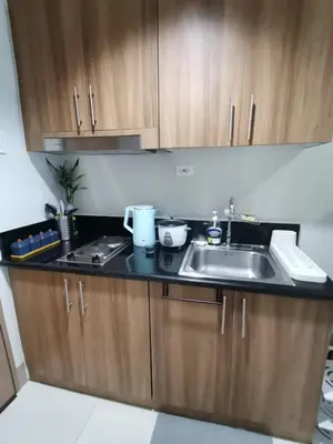 a kitchen with wooden cabinets and a sink at Clarquin Residences - Shore 3 Residences Tower 2 in Manila