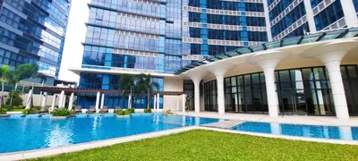 a large building with a swimming pool in front of a building at Spacious Modern Suites with Amazing City View in Manila