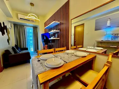 a dining room with a table and a living room at Shore 3 Residences - HTZ Haven in Manila