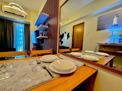 a table with plates and glasses on top of it at Shore 3 Residences - HTZ Haven in Manila