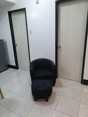 a chair and a stool in a room with two doors at A place to relax & have privacy in Manila