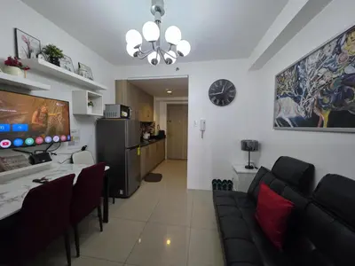 a living room with a couch and a table and a clock at Ethans Place in Manila