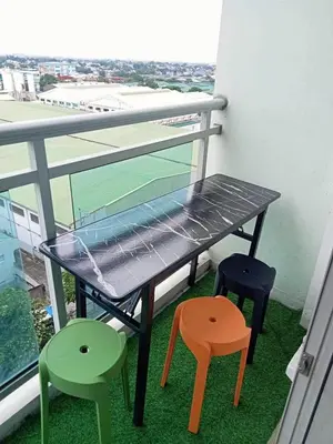 a table with four colorful chairs on a balcony at 2BR condo Azure Netflix, Karaoke & Board games in Manila