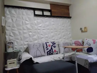a living room with a couch with pillows on it at Breeze Residences in Manila