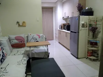 a kitchen with a refrigerator and a table in a room at Breeze Residences in Manila