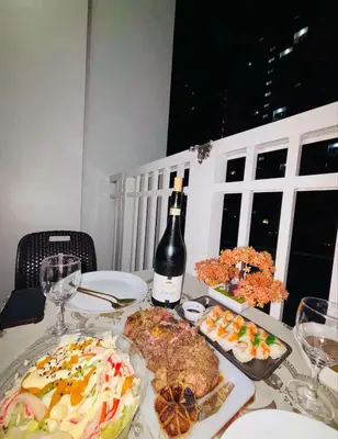 a table with a plate of food and a bottle of wine at AZs Staycation in Manila