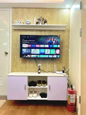 a flat screen tv on a wall with a white cabinet at Veronica Grey's Staycation 2BR in Manila